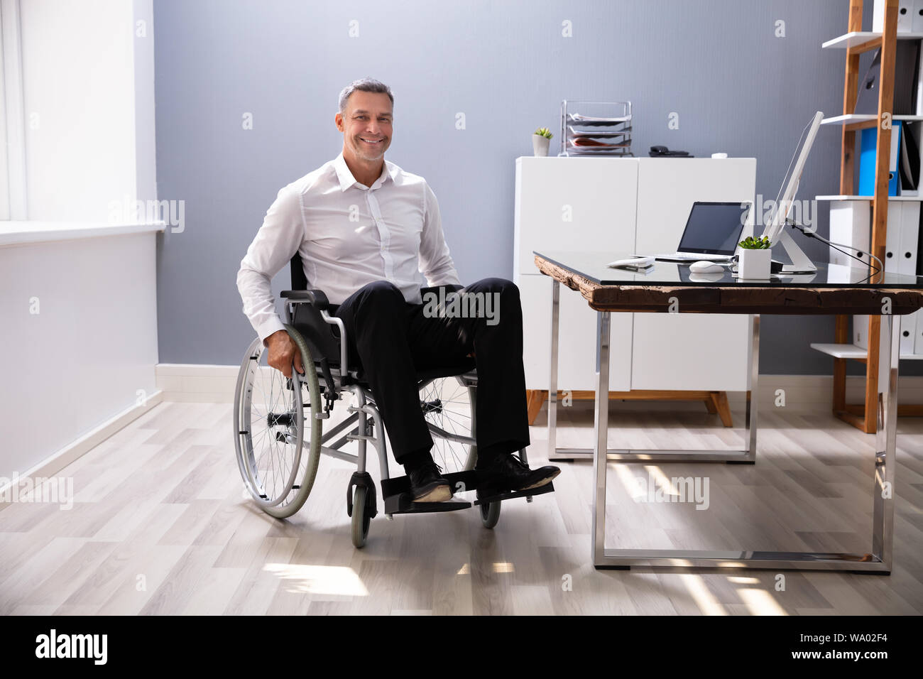 Homme d'handicapés assis sur fauteuil roulant dans Office Banque D'Images