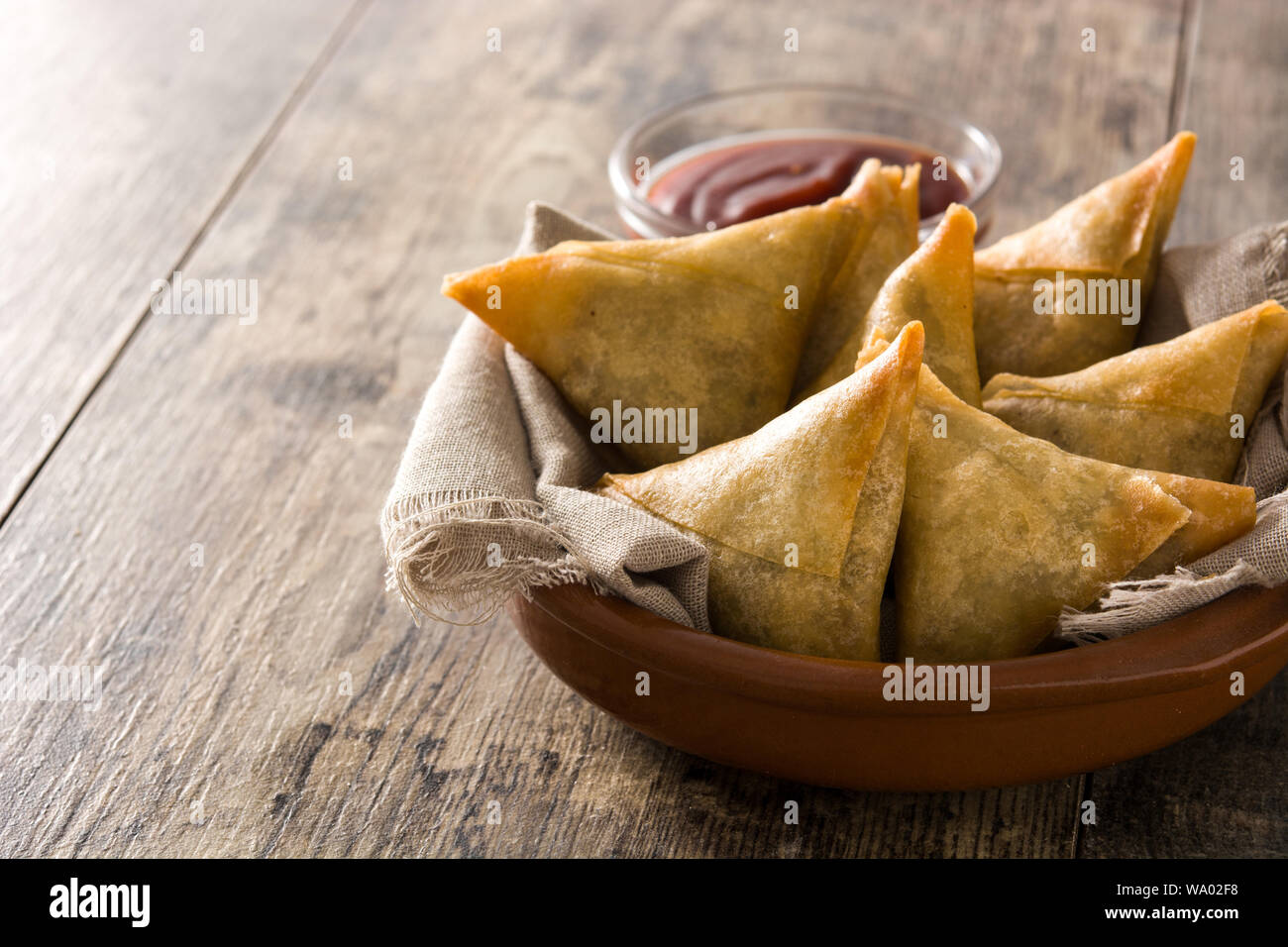 Samsa ou samossas à la viande et les légumes dans un bol sur la table en bois. La cuisine indienne traditionnelle. Copyspace Banque D'Images