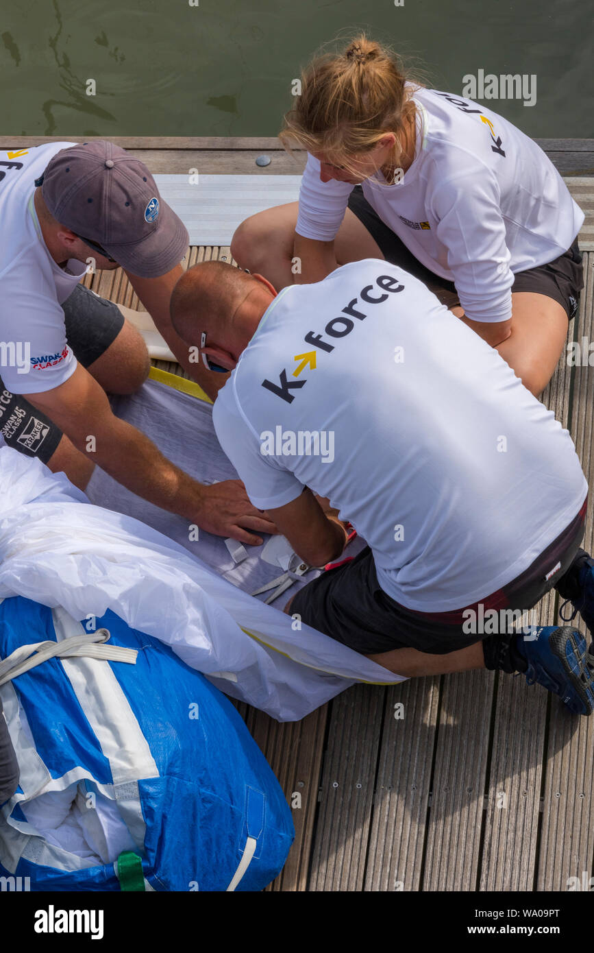 Un jeune équipage de bateaux travaillant ensemble en équipe pour faire une voile sur le ponton pendant la régate annuelle coves eek sur l'île de Wight. Banque D'Images