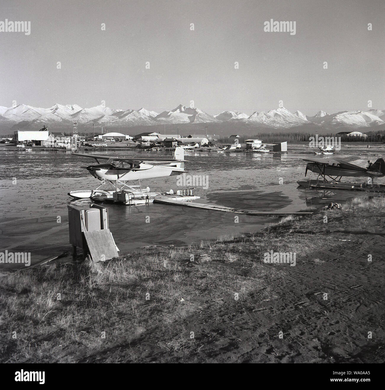 Années 1950, historiques, les hydravions au lac des Bois à côté de l'aéroport de Anchorage, Alaska, USA avec les montagnes Chugach en arrière-plan. Banque D'Images