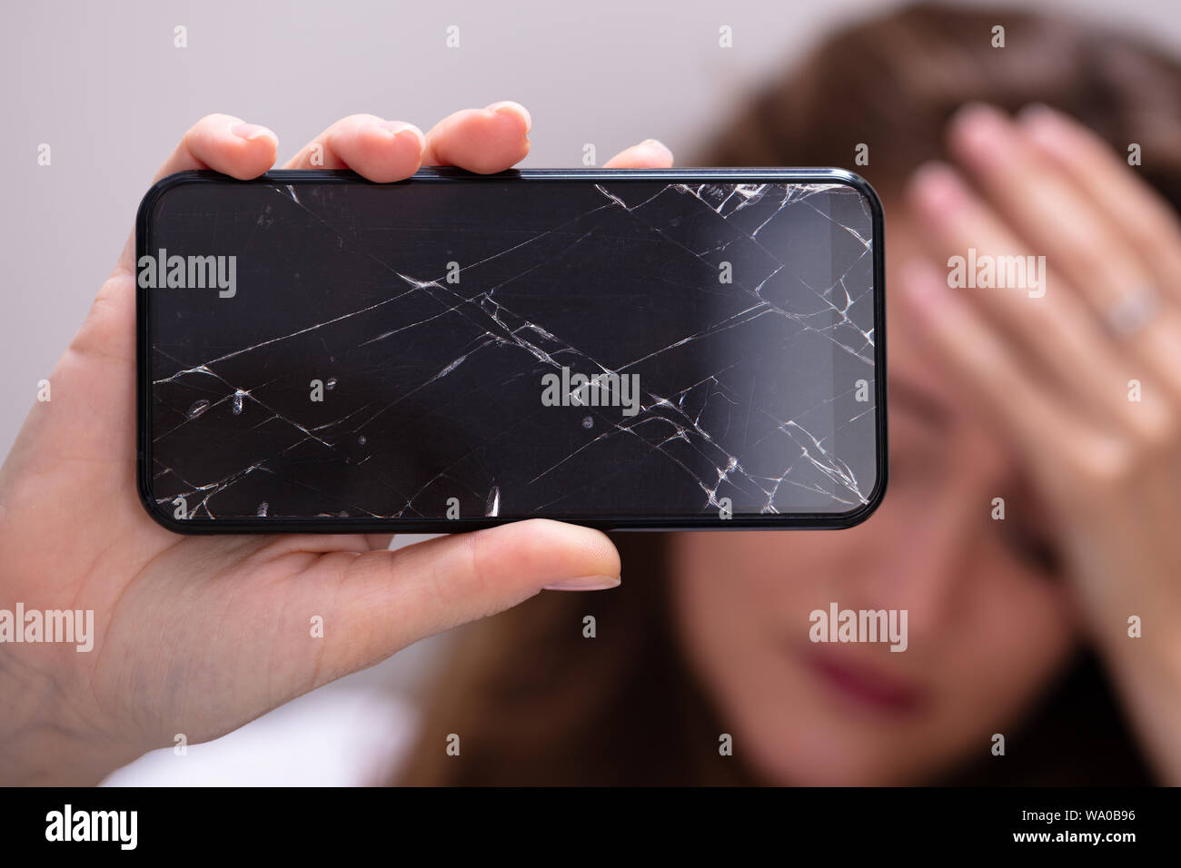 Woman Holding Smartphone avec écran fissuré Banque D'Images