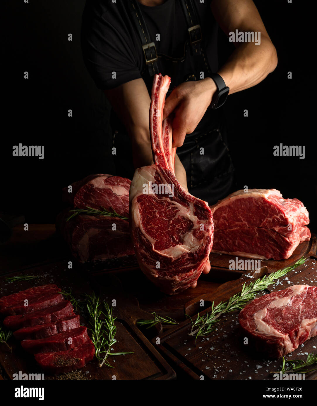 Les mains d'un homme montrant un carré d'os long Ribeye Steak. Image clé faible, orientation verticale. Banque D'Images Les mains d'un homme montrant un carré d'os long Ribeye Steak. Image clé faible, orientation verticale. Banque D'Images