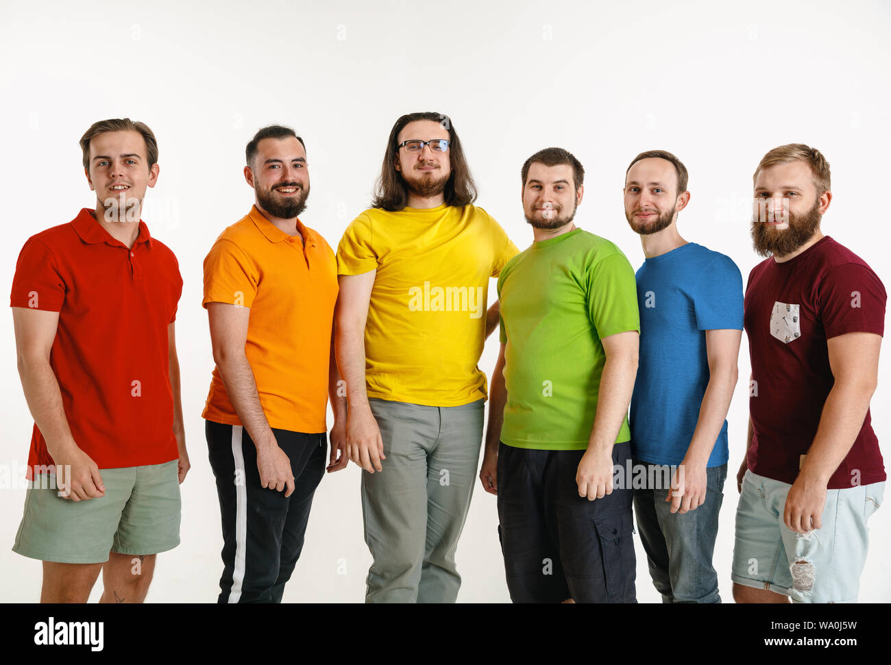 Les jeunes hommes portée dans les couleurs du drapeau LGBT isolé sur fond blanc. Homme de race blanche dans les modèles de chemises rouge, orange, jaune, vert, bleu et violet. La fierté LGBT, des droits de l'homme et choix concept. Banque D'Images