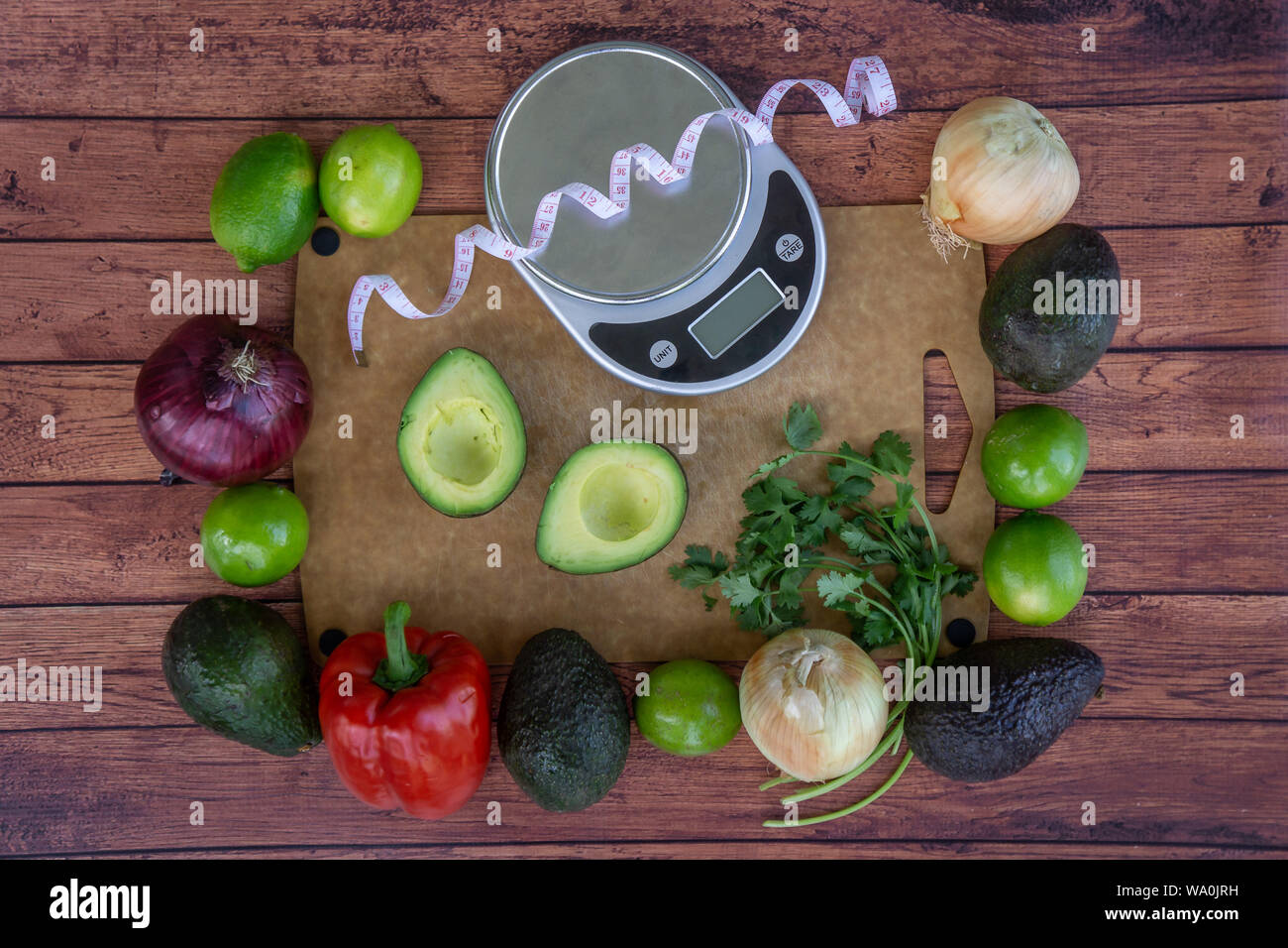 Haut de la vue de dessus de la guacamole frais ingrédients avec échelle de poids et ruban à mesurer. L'avocat coupé en deux, la coriandre fraîche, poivron rouge, vert lim Banque D'Images