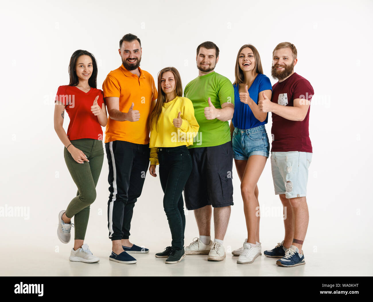 Jeune homme et femme portée au drapeau LGBT couleurs sur fond blanc. Modèles de race blanche dans des chemises. L'air heureux, souriant et serrant. La fierté LGBT, des droits de l'homme et choix concept. Banque D'Images