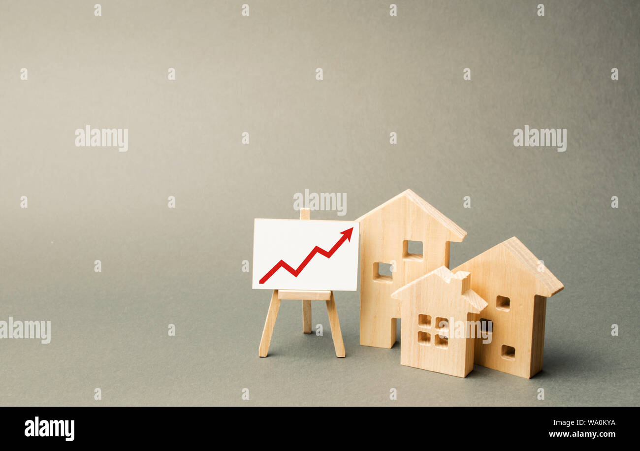 Trois maisons en bois et une flèche rouge sur le signe. Augmenter la valeur de l'immobilier. Des taux élevés de construction, forte liquidité. L'offre et de la demande. La hausse Banque D'Images