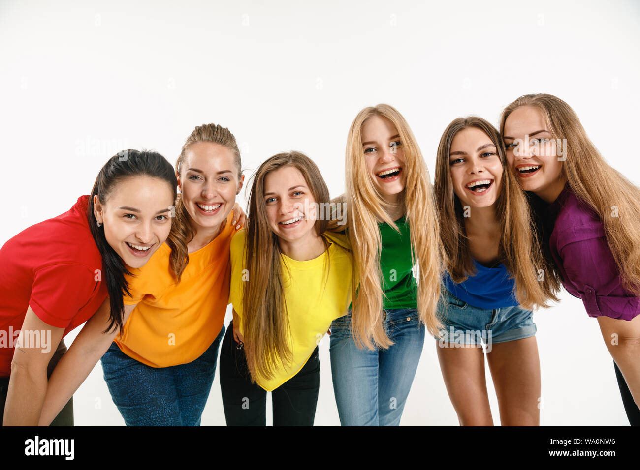 Les jeunes femmes portée en couleurs du drapeau LGBT isolé sur fond blanc. Portrait des modèles féminins dans des chemises. L'air heureux, souriant. Fierté LGBT de fiducie, des droits de l'homme, concept de la liberté de choix. Banque D'Images