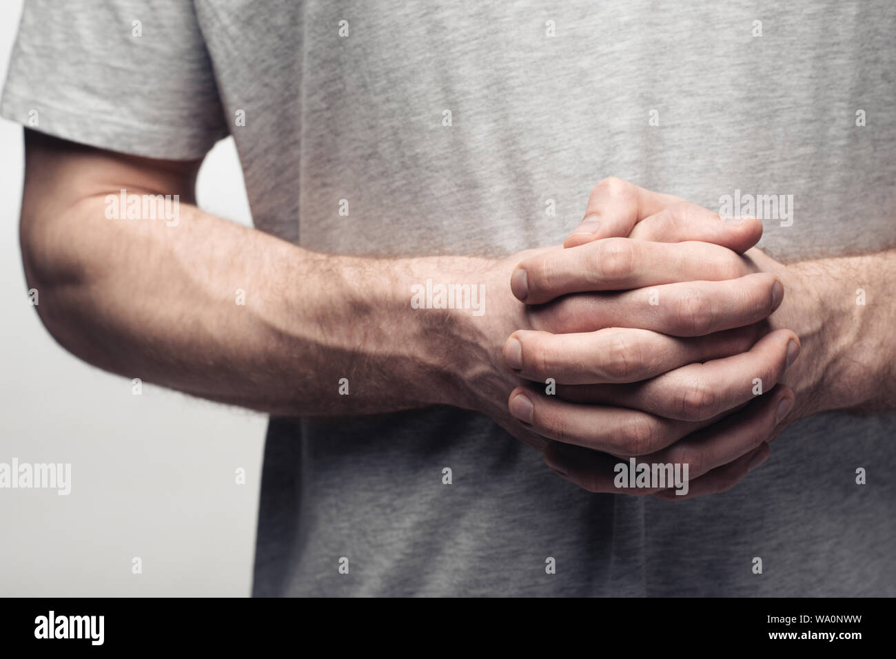 Portrait de l'homme debout avec les mains serrées isolé sur gray, l'émotion et d'expression concept Banque D'Images
