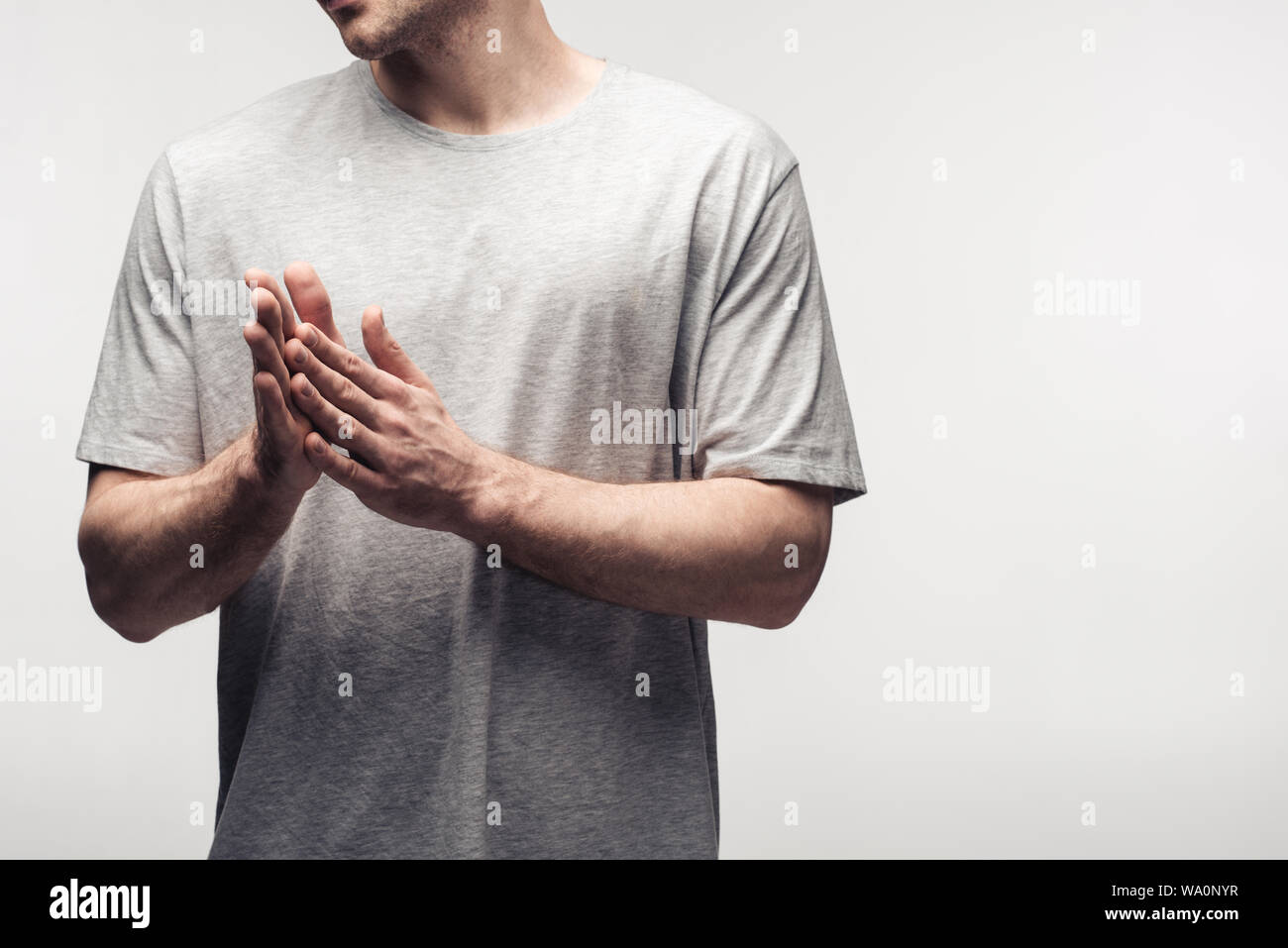 Portrait de l'homme en frottant les mains isolé sur gray, l'émotion et d'expression concept Banque D'Images