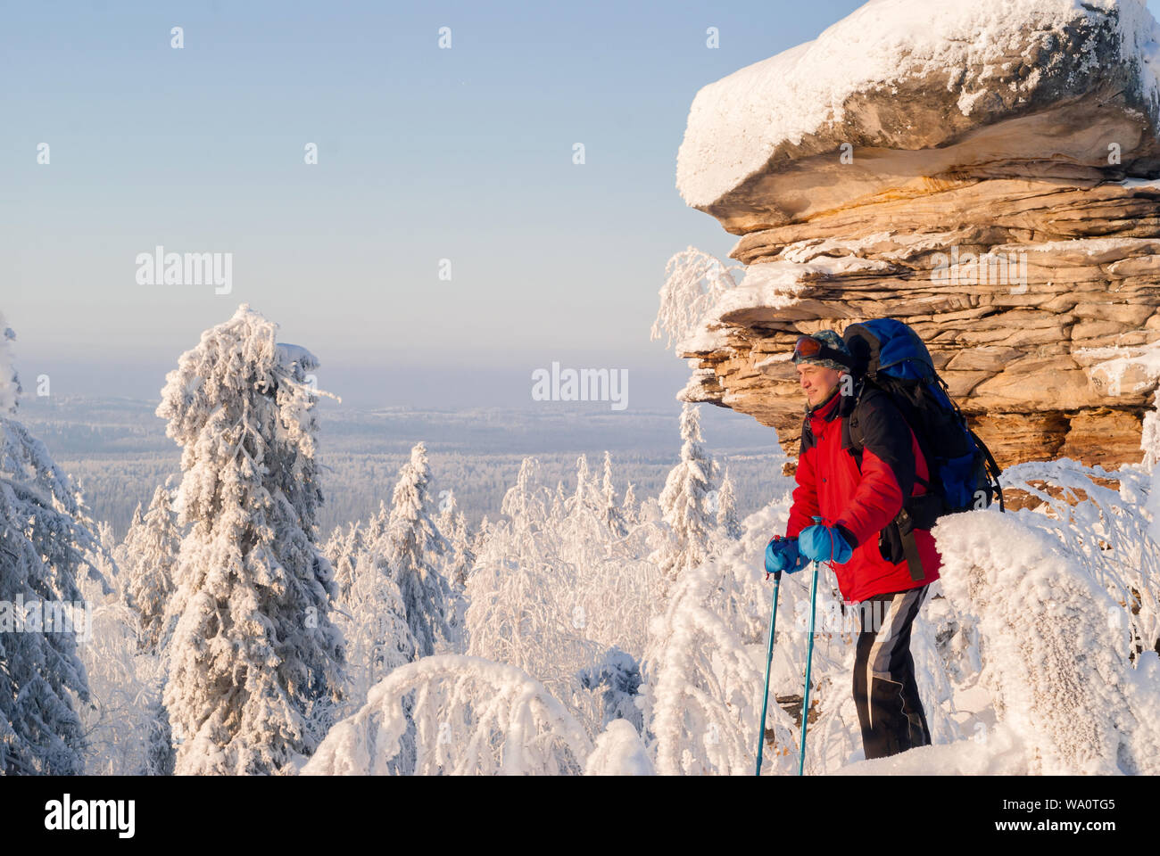 Voyageur avec sac à dos et des bâtons pour la marche nordique debout dans un hiver glacial paysage près d'une belle falaise et regarde dans la distance Banque D'Images
