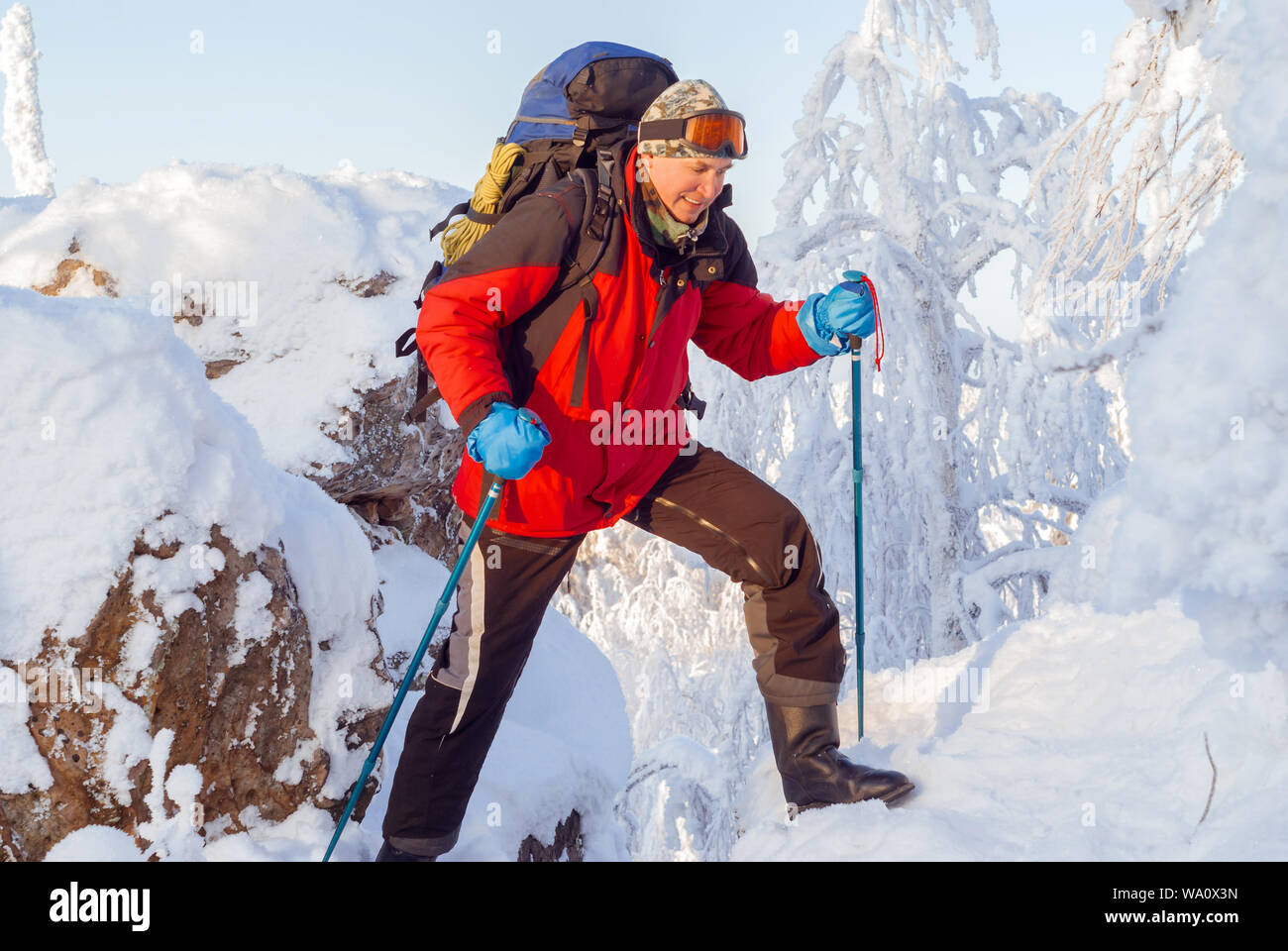 Dans l'hiver homme backpacker surmonte la montagne la crevasse entre les rochers couverts de neige Banque D'Images
