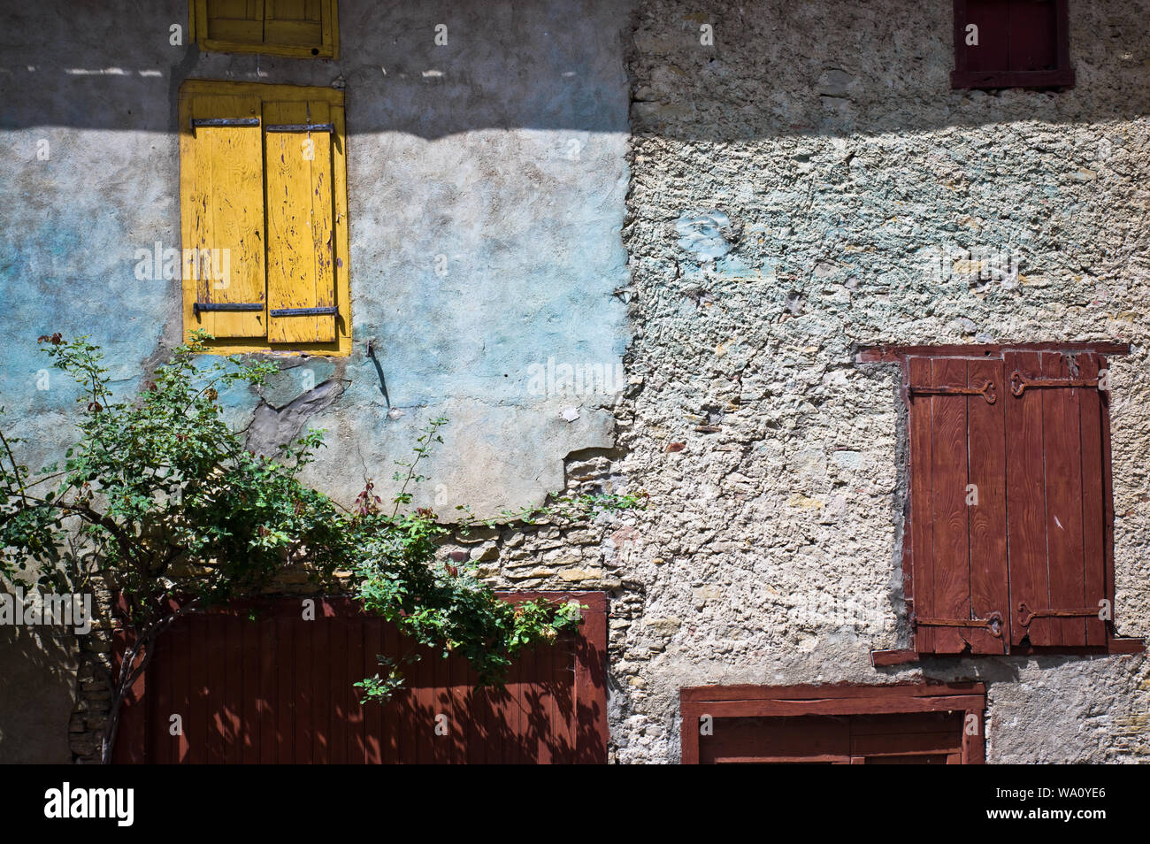 Détail d'un mur en pierre avec des fenêtres peintes dans le village historique de Camon. Ariège, France. Banque D'Images