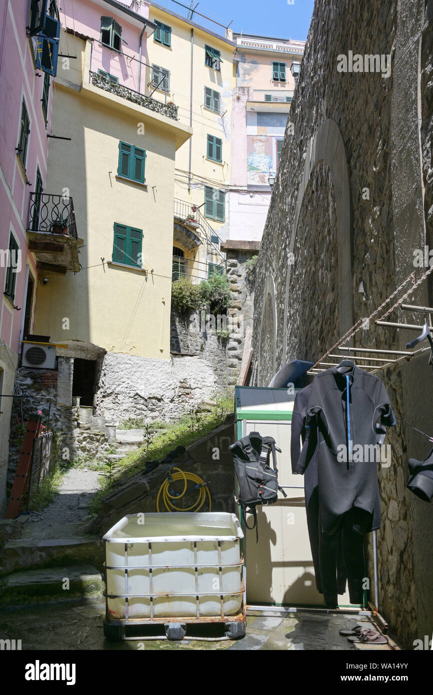 Scaphandres accroché à côté d'un grand bain à remous de l'eau dans une vieille ruelle de Riomaggiore, Cinque Terre, Italie Banque D'Images