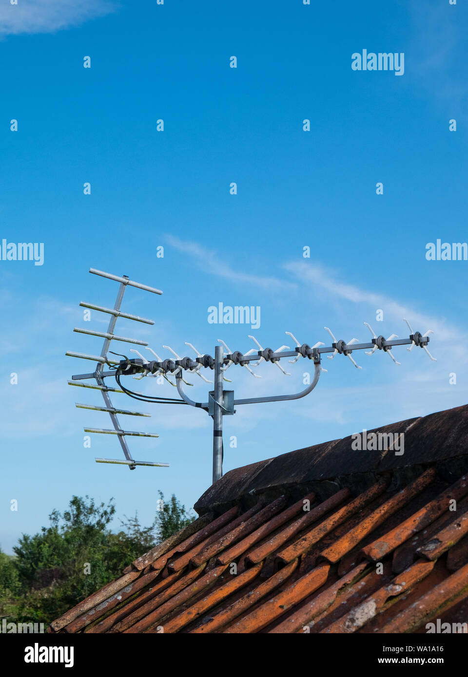 Une antenne TV numérique sur le toit d'une maison contre un ciel bleu Banque D'Images
