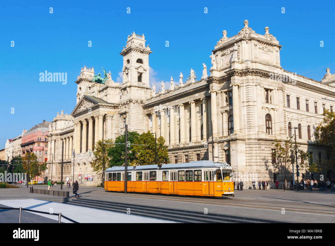 La Place Kossuth avec tram jaune et le Musée Ethnographique s'appuyant sur une terrasse bien afteroon. Budapest, Hongrie. Banque D'Images