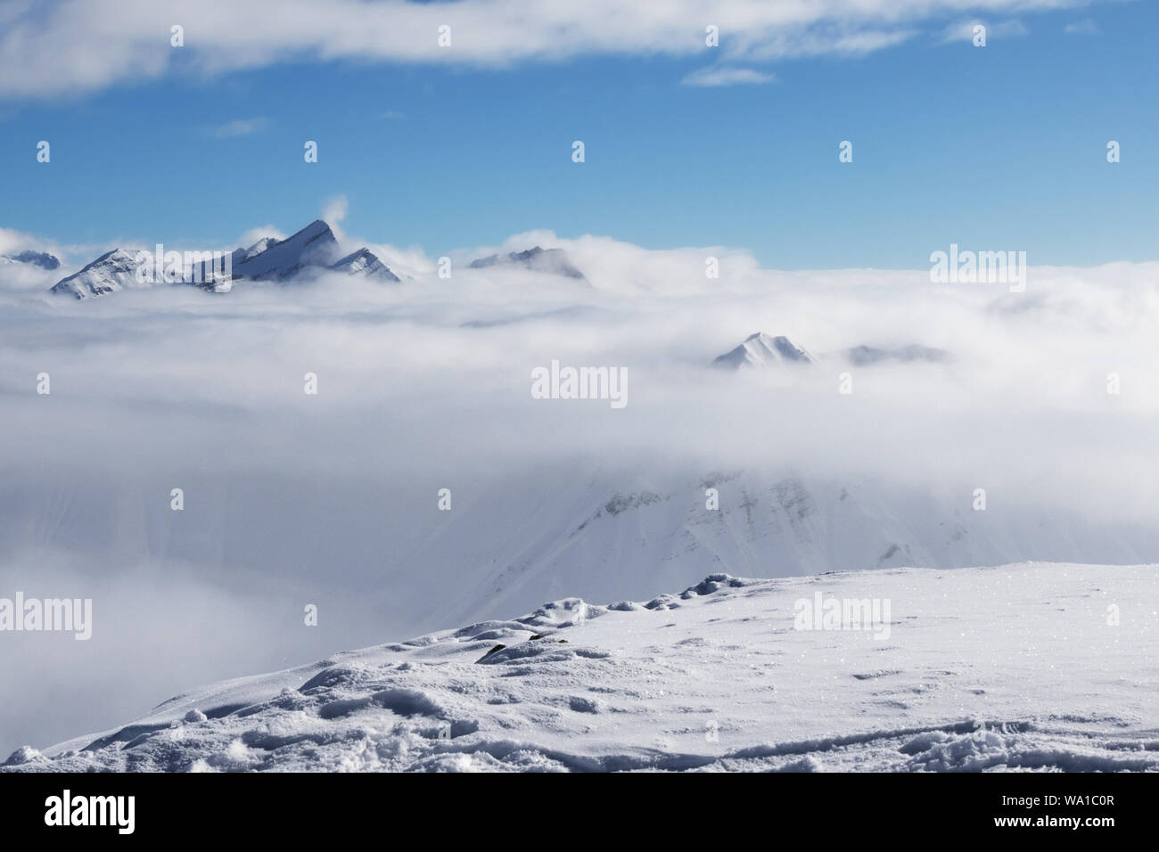 Pente couverte de neige et soleil, montagnes sous les nuages à belle journée ensoleillée. Montagnes du Caucase en hiver, la Géorgie, la région Gudauri. Kudebi point de vue au sommet du mont. Banque D'Images