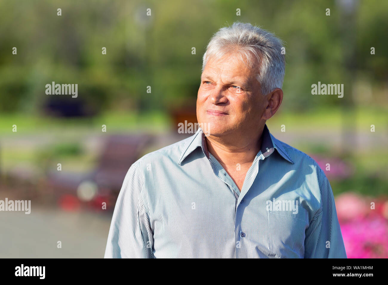 Bel homme âgé dans une chemise bleue dans un parc de la ville. Banque D'Images