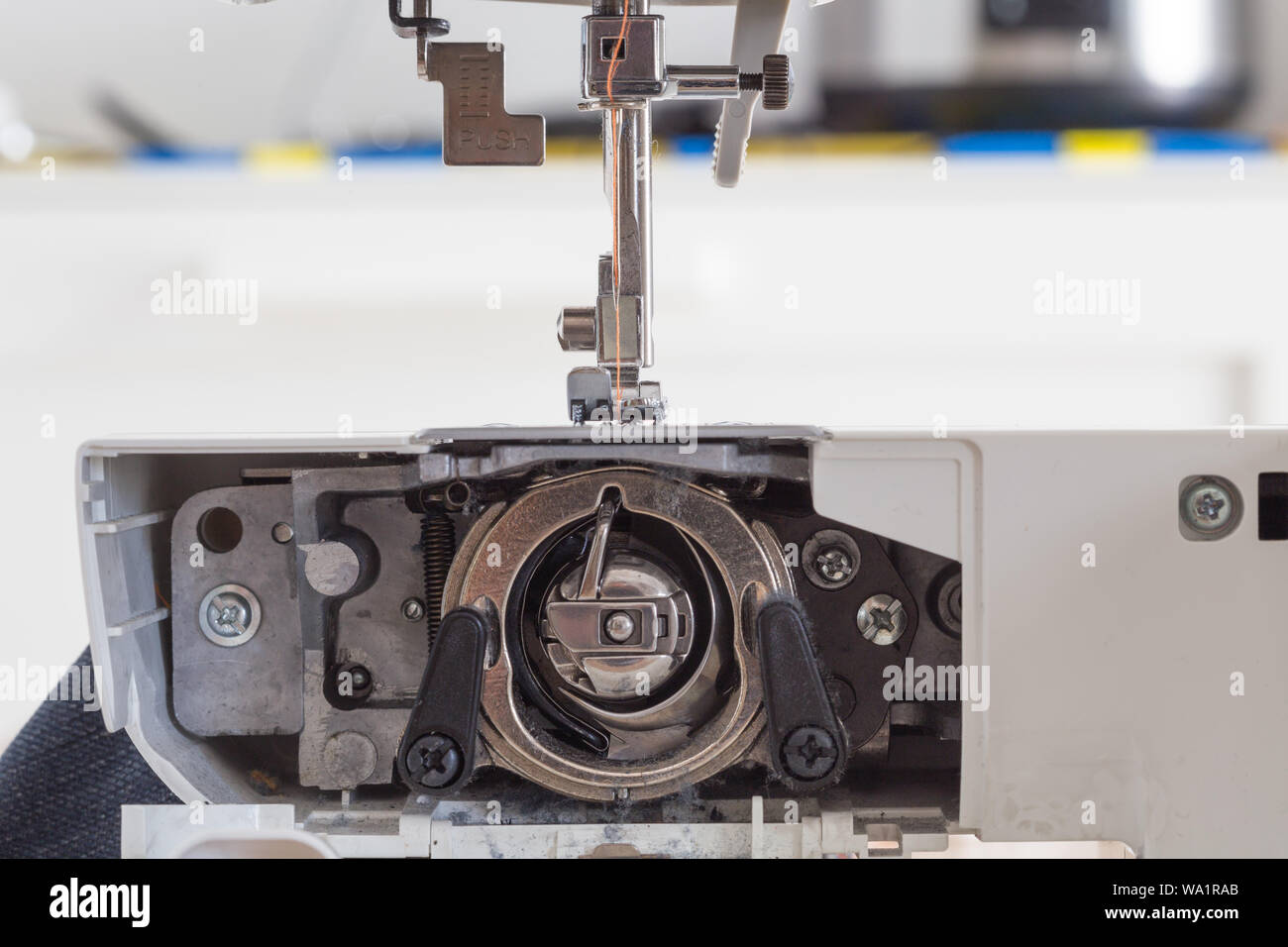 Machine à coudre avec aiguille et fil de couleur sur une table avec arrière-plan flou, table de travail du tailleur, du textile ou de tissu fin, tissu industriel, Banque D'Images