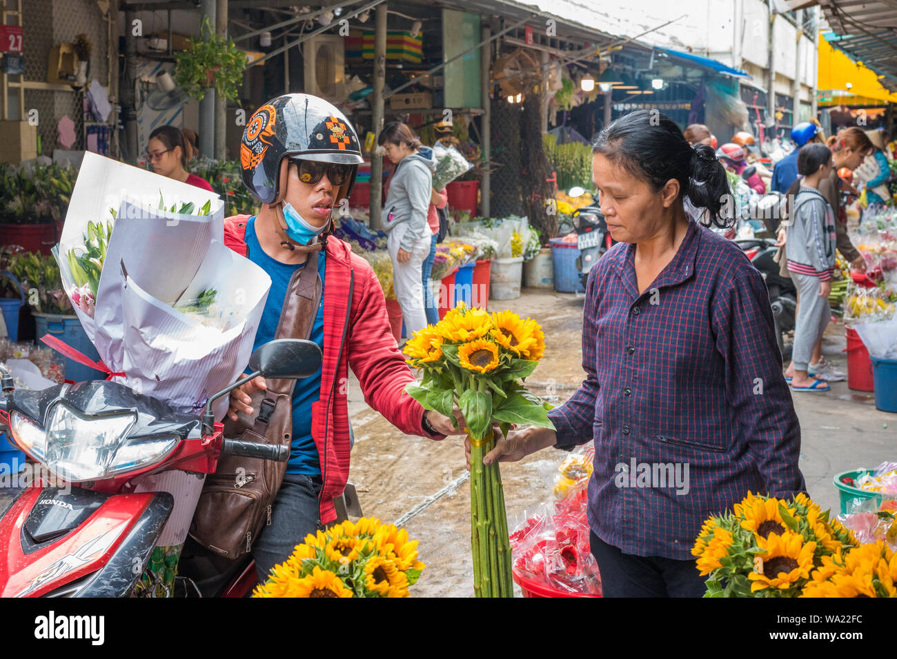 Ho Chi Minh Ville, Vietnam - 12 Avril 2019 : une femme sur moto achète un bouquet de fleurs d'un fournisseur à l'Ho Thi Ky Marché aux Fleurs. Banque D'Images