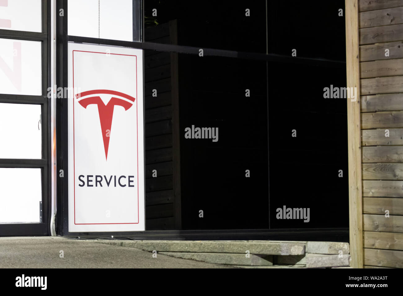 Service Tesla affiche à l'extérieur d'un centre de service de nuit. Banque D'Images Service Tesla affiche à l'extérieur d'un centre de service de nuit. Banque D'Images