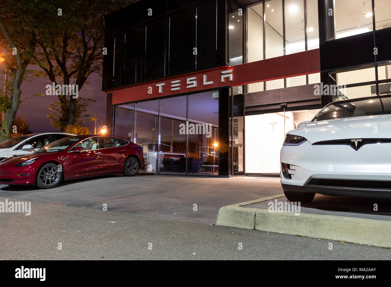 Entrée du concessionnaire Tesla avec de nouveaux véhicules stationnés à l'avant, tard dans la nuit. Banque D'Images