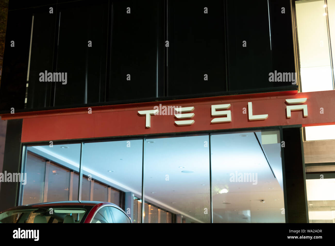 Logo texte Tesla sur-haut de Showroom Tesla et un centre de services de nuit. Banque D'Images