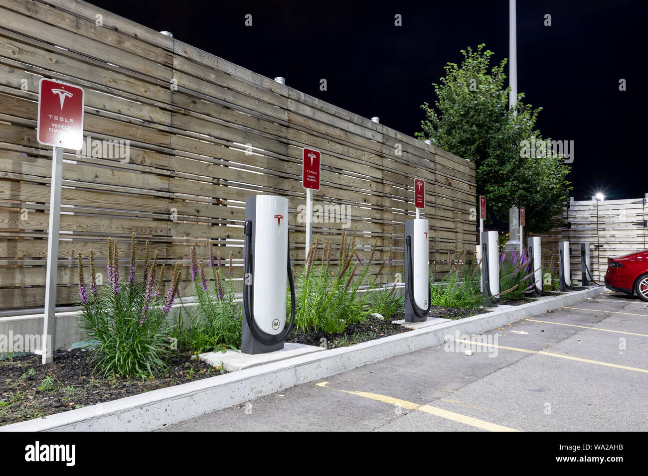 Tesla Supercharger Gare vu par une nuit claire avec véhicule connecté sur secteur. Banque D'Images Tesla Supercharger Gare vu par une nuit claire avec véhicule connecté sur secteur. Banque D'Images