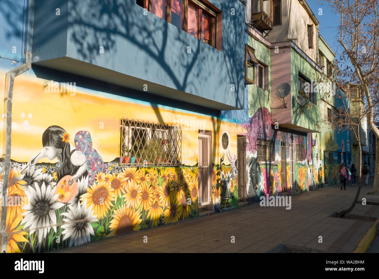 Les piétons à pied passé murales sur les bâtiments en bois à Bellavista, Santiago, Chili Banque D'Images