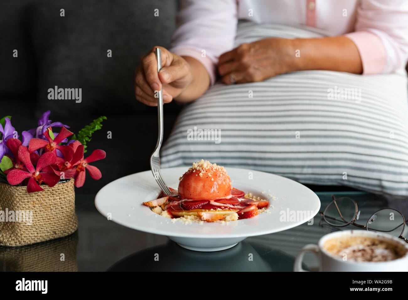 La vieille femme tient du folk avec des crêpes fraîchement faites maison, la Crumble aux fraises sur la plaque de dessert blanche Banque D'Images