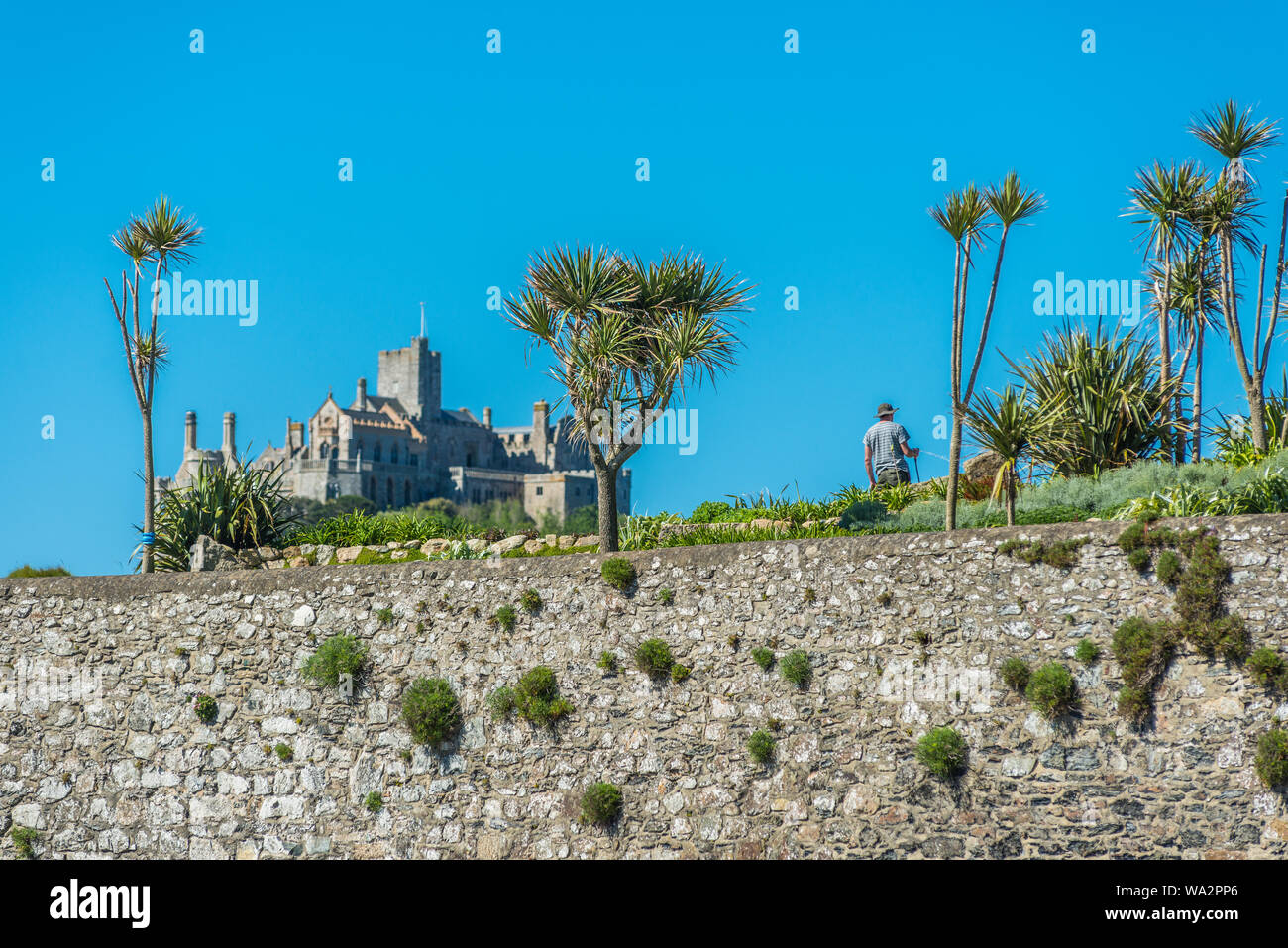 Un jardinier tendant son jardin sur le bord de l'eau dans le village de caractère de Marazion (St Michael's Mount), Cornwall, England, UK. Banque D'Images