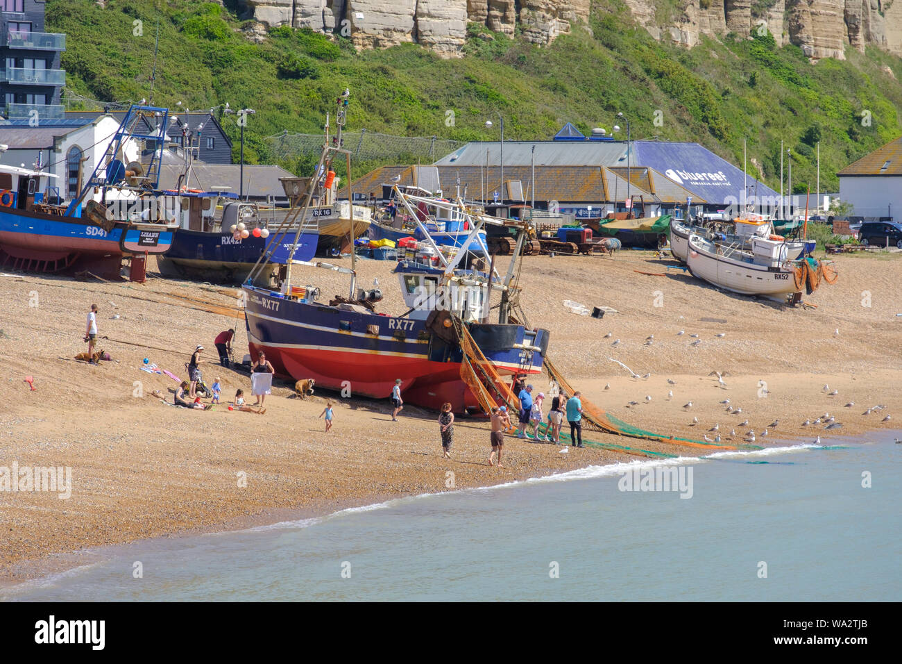 Bateau de pêche Hastings d'être tiré jusqu'à l'Ancien hôtel de ville Stade bateau de pêche plage, les gens à jeter à crabes capturés dans des filets de pêche, East Sussex, Banque D'Images