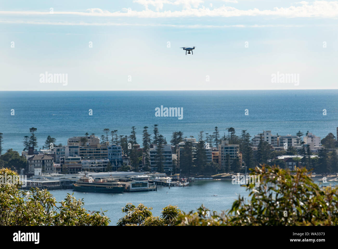 Avec un Ferry Sydney amarré à l'arrière-plan à Manly wharf et la banlieue de Manly derrière elle un bourdon suspendu au-dessus avec une vue panoramique Banque D'Images