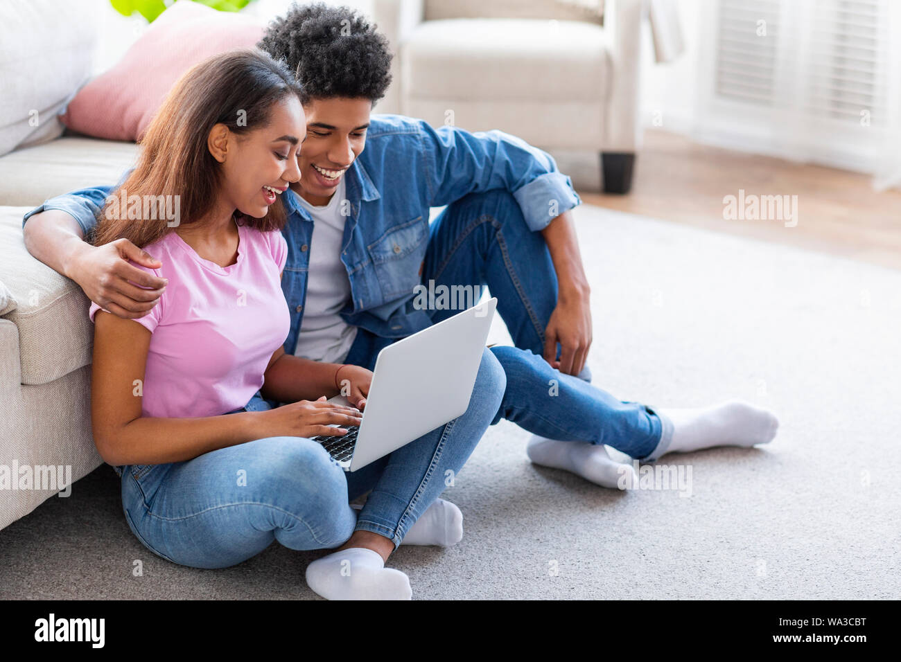 Black teen couple using laptop sitting on floor Banque D'Images