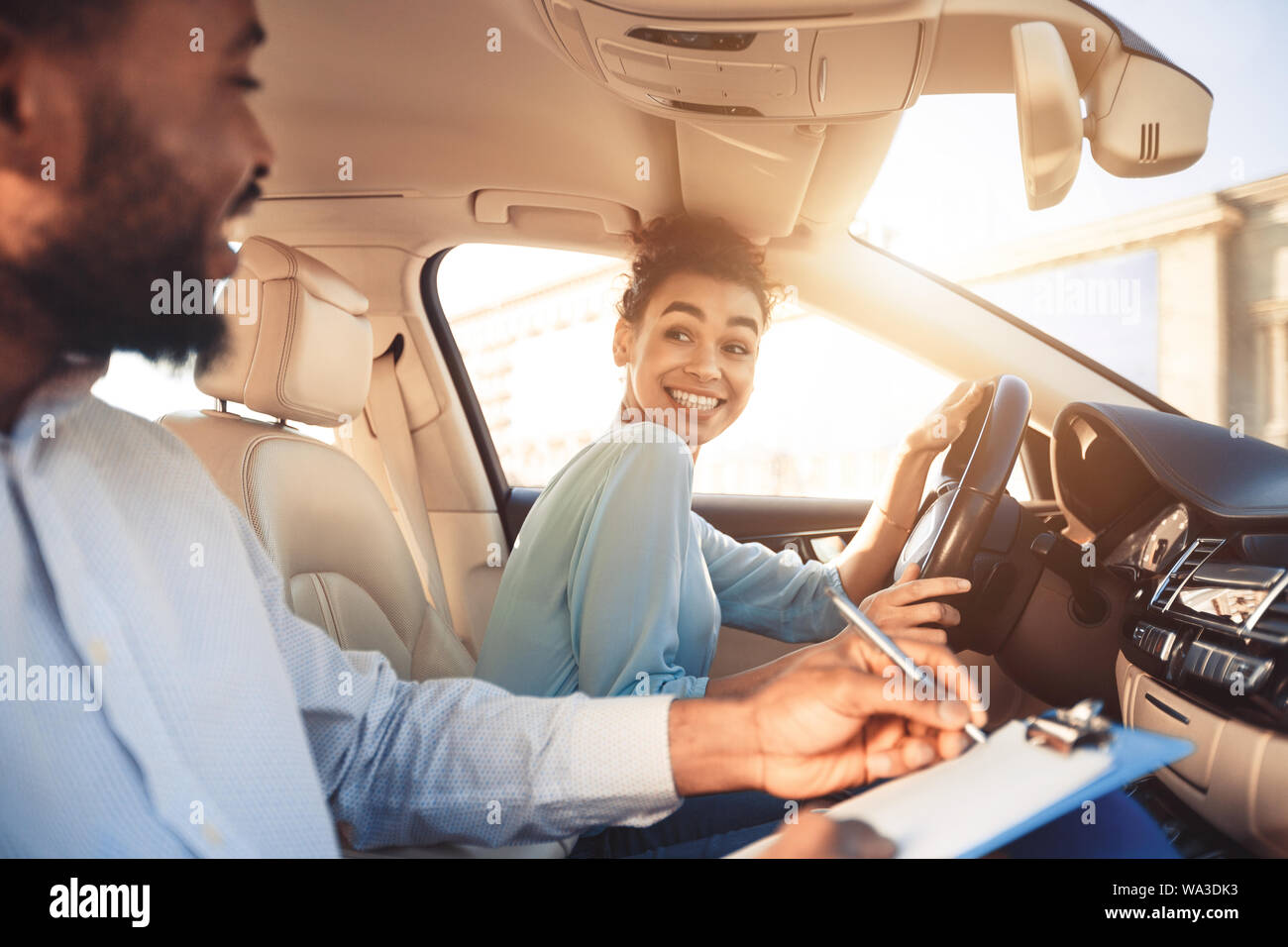 Femme heureuse en matière d'examen voiture, souriant pour instructeur mâle Banque D'Images