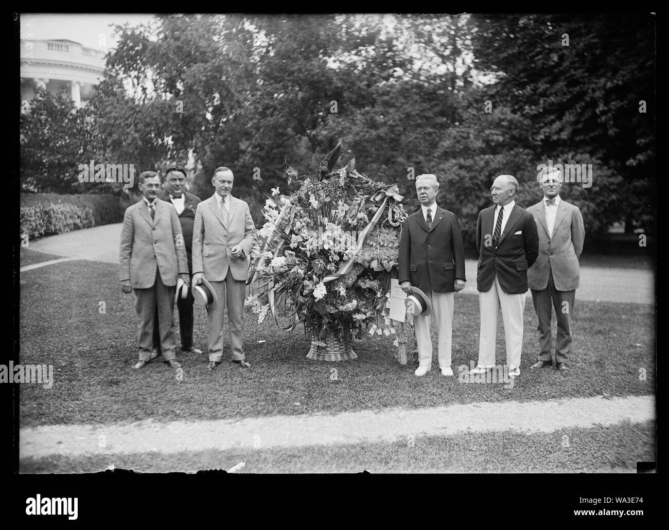 Voeux d'anniversaire de les fleuristes du pays ont été présentés aujourd'hui par le Président Coolidge dirigeants et administrateurs de la Telegraph Fleuristes Assoc. de livraison sous la forme d'une cloche de la liberté faite avec des fleurs. Le 4 juillet est l'anniversaire du président. Lft. à rt.:Wallace McCamant, de Portland, Oregon, qui a proposé le Président Coolidge pour la vice-présidence il y a quatre ans ; Wm. F. Gude, Président Coolidge, Edw. Sceery, Chas. H. Brown, et J.R. Le Daly [Maison Blanche, Washington, D.C.] Banque D'Images