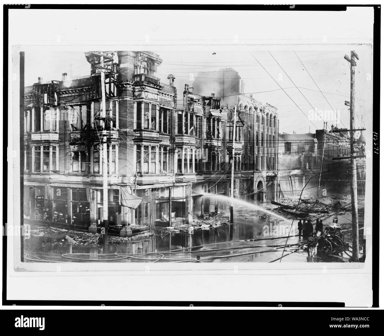 Bloc de bâtiments brûlés à San Francisco après le tremblement de terre de 1906 avec un camion à incendie pulvériser de l'eau sur eux Banque D'Images