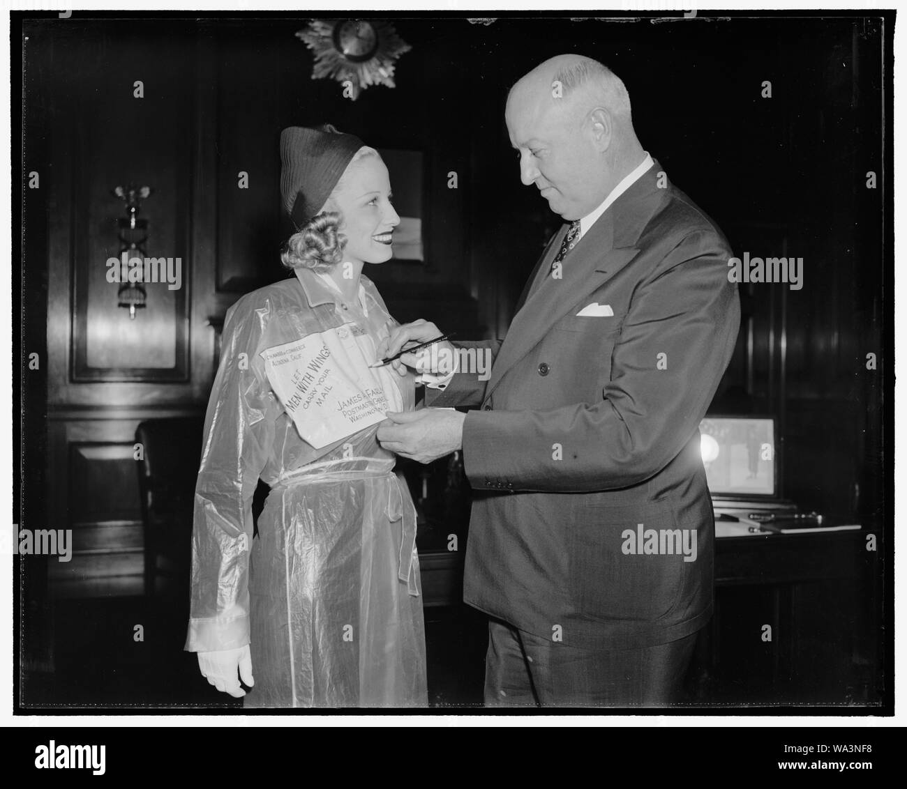 Pour le courrier aérien blonde ministre des Postes. Washington, D.C., le 18 mai. Ministre des postes James A. Farley, signes d'un paquet de beauté envoyé, par avion, à partir de l'ancienne aéropostale pilotes qui participent à la production de Paramount avec des ailes d'une histoire de l'histoire de la poste aérienne. Le paquet se trouve être Mlle Marion Weldon, qui est à Washington de prendre part à la semaine nationale de la poste aérienne, et est aussi joué dans les hommes avec des ailes, 5/18/38 Banque D'Images