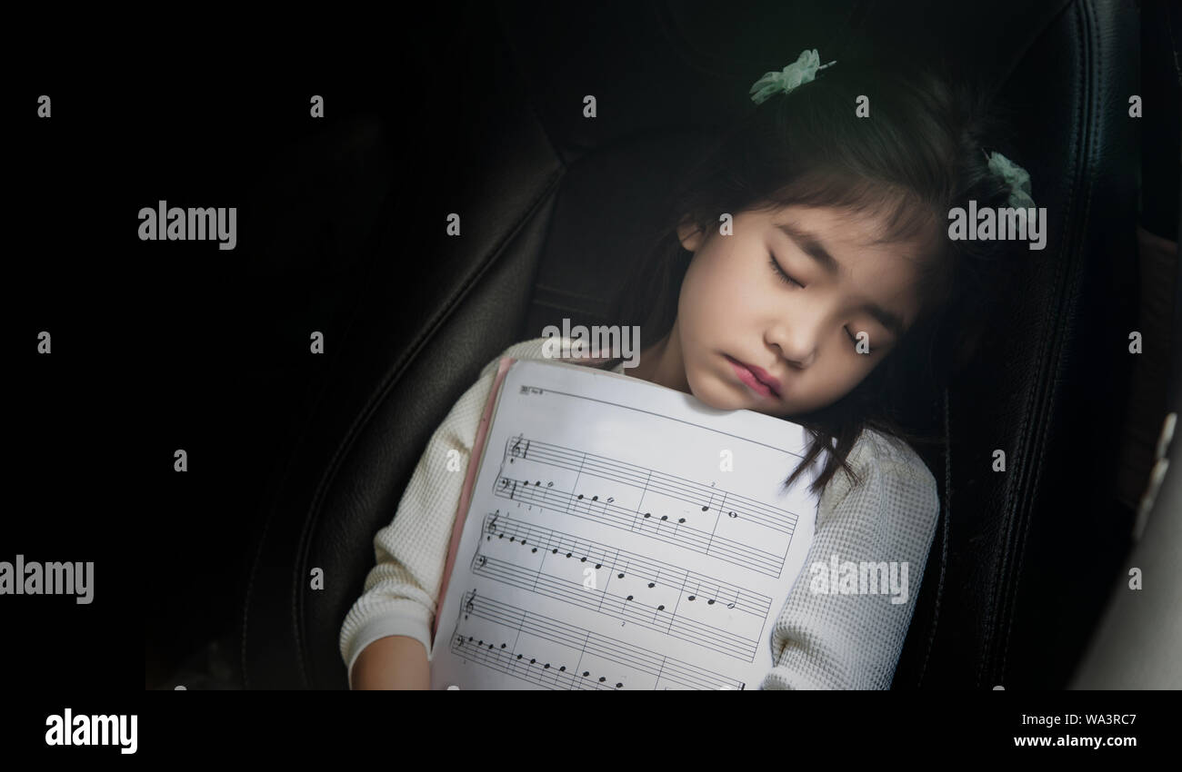 Kid sleep avec note de musique sur le siège voiture aussi aime la musique concept. Passer du temps sur l'auto pour enfants Banque D'Images