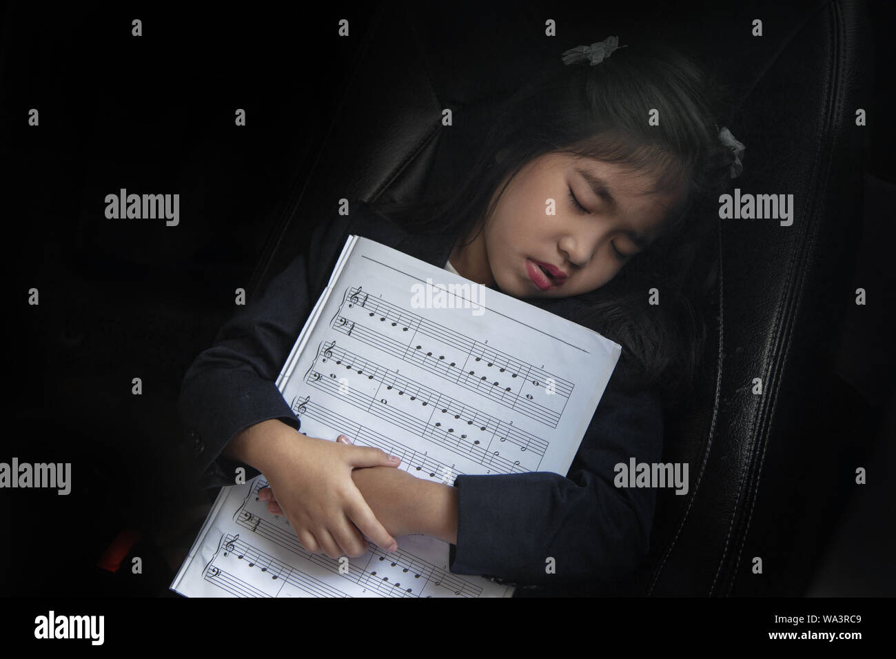 Kid sleep avec note de musique sur le siège voiture aussi aime la musique concept. Passer du temps sur l'auto pour enfants Banque D'Images