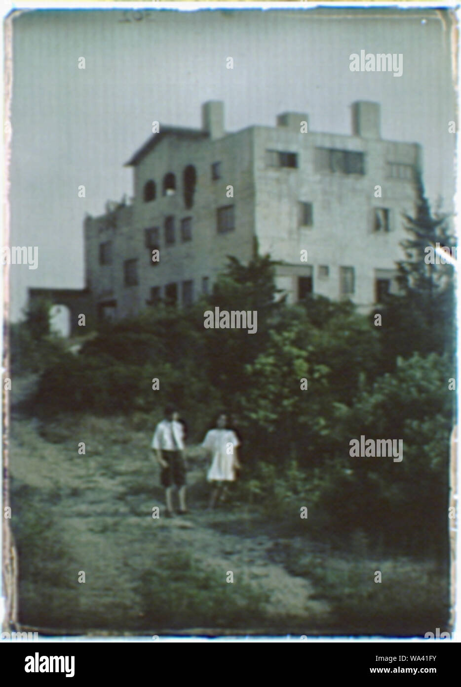 Garçon et fille debout sur un chemin de terre menant à une maison de trois étages Banque D'Images
