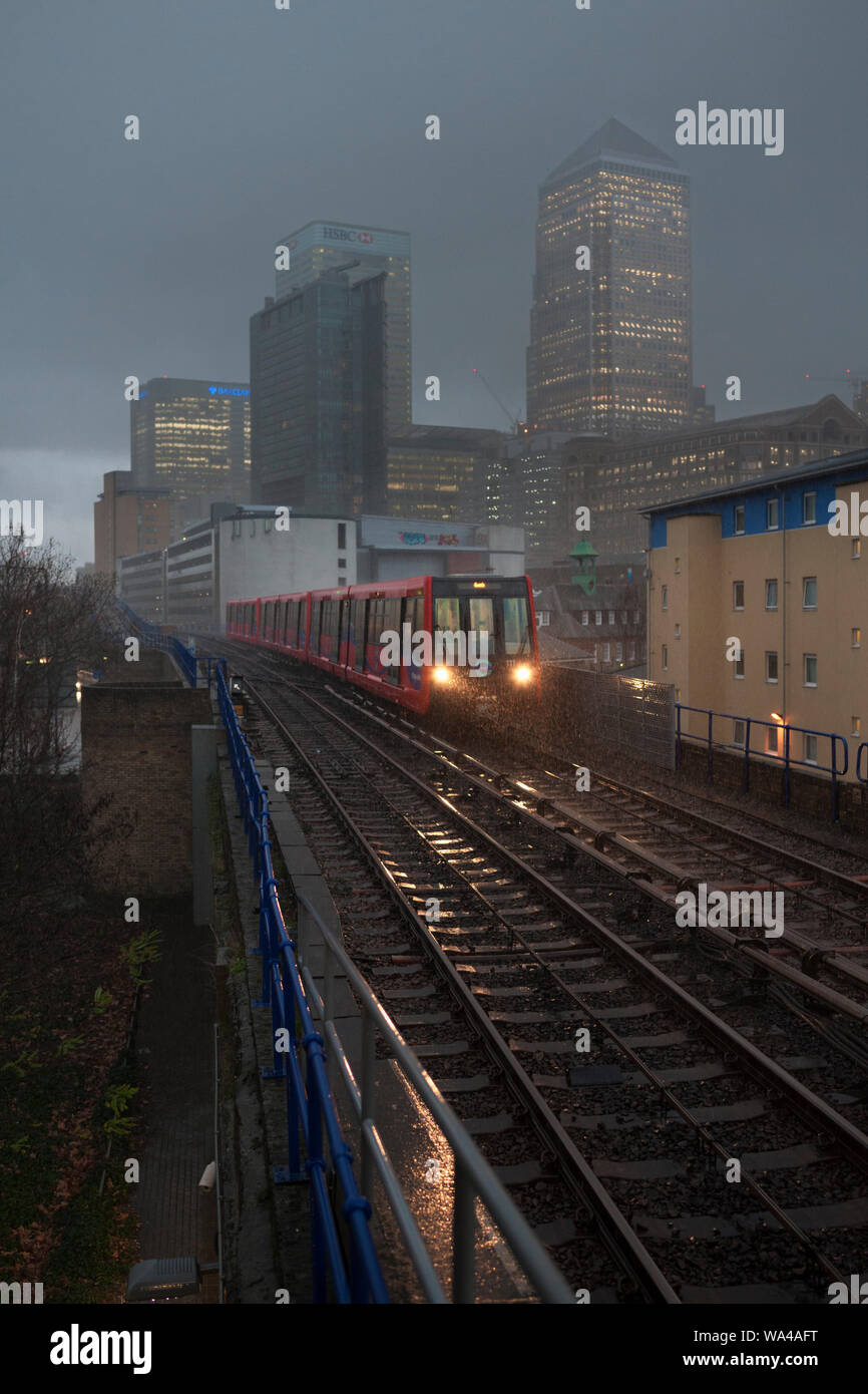 Westferry, London Docklands Light Railway 111  + 136  + 104 en arrivant sur une journée humide dans un orage avec une banque publique, Canary Wharf est derrière Banque D'Images