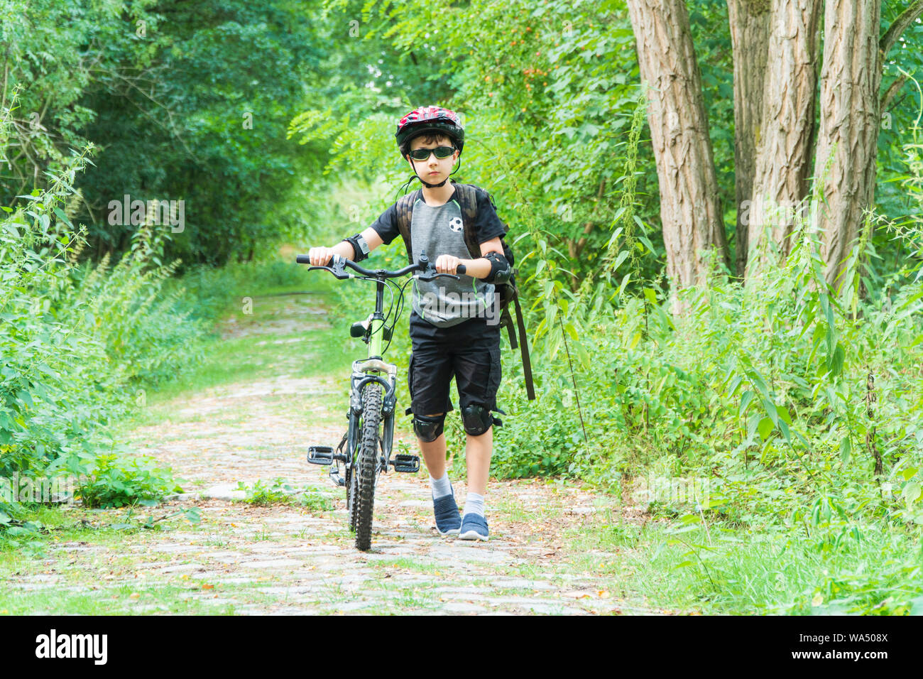 School boy dans le casque de protection riding bike dans le parc Banque D'Images