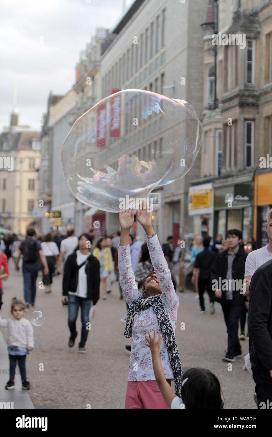 Jeune femme à atteindre touch large bulle de savon en pic de la rue © Jack Ludlam Banque D'Images