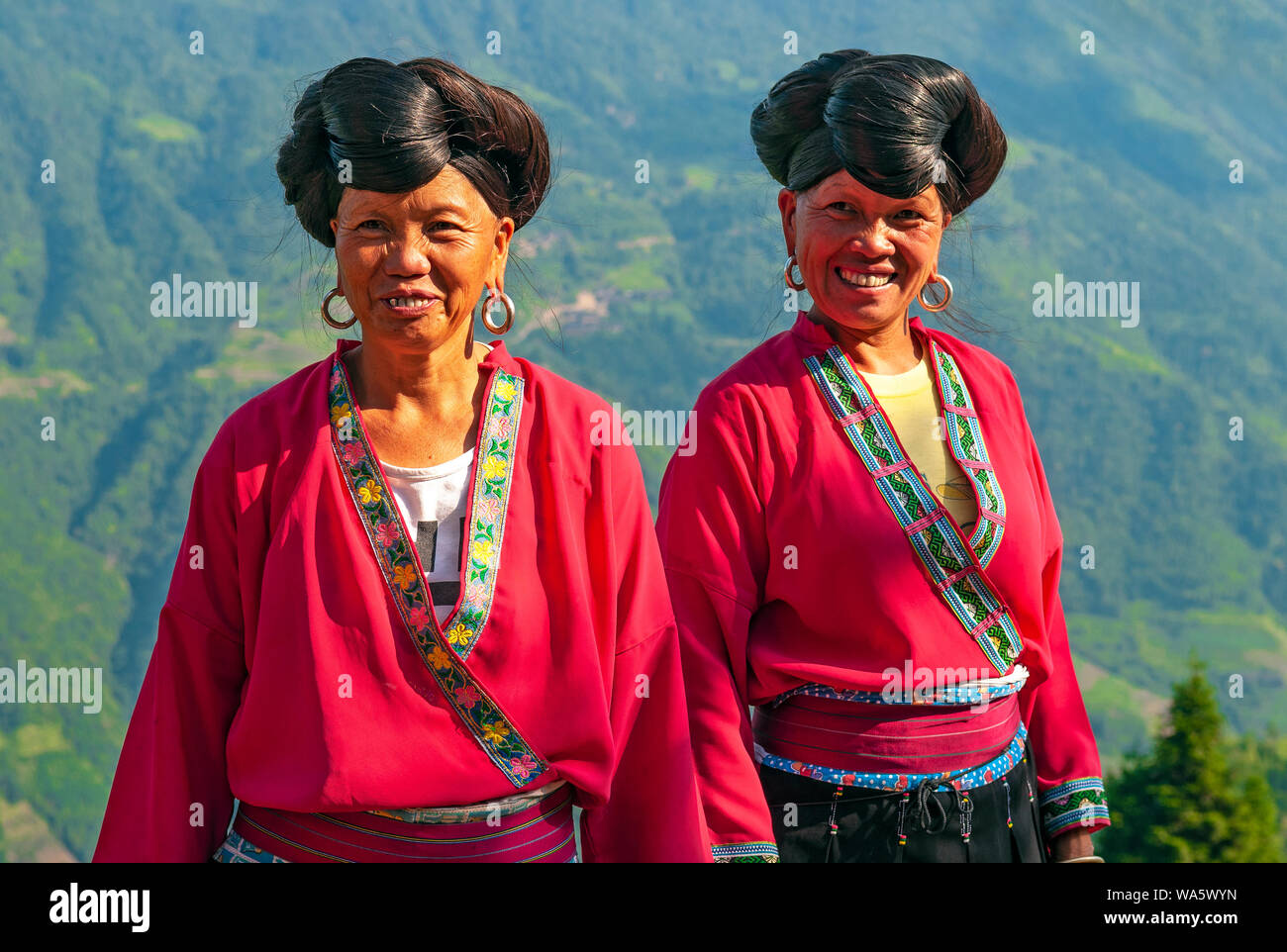 Les femmes aux cheveux longs souriant du groupe ethnique Yao par les rizières en terrasses de Longsheng Ping An dans la province du Guangxi, Chine. Banque D'Images