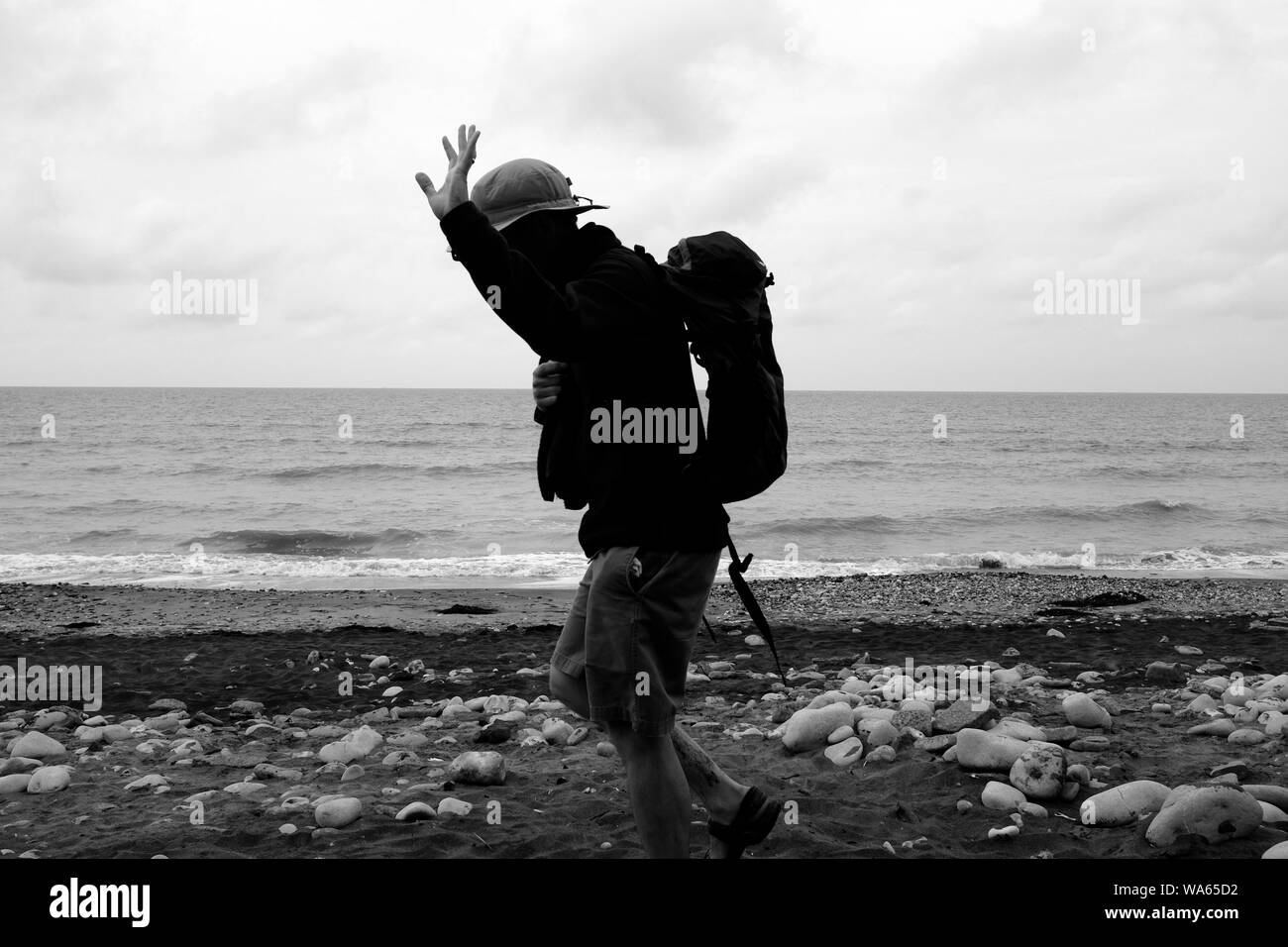 Une marchette de quitter la plage et salué avec un sac à dos sur le dos, chapeau sur la tête et marcher dans sa main pôle Banque D'Images