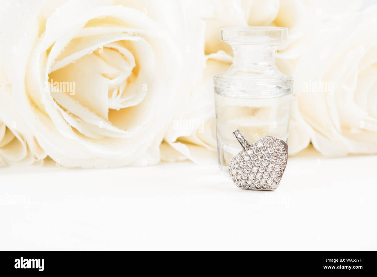 Cadeau de Saint-Valentin avec bouquet de roses blanches, parfum et coeur pendentif avec diamants. Copier l'espace. Soft focus. Cadeau de mariage Banque D'Images