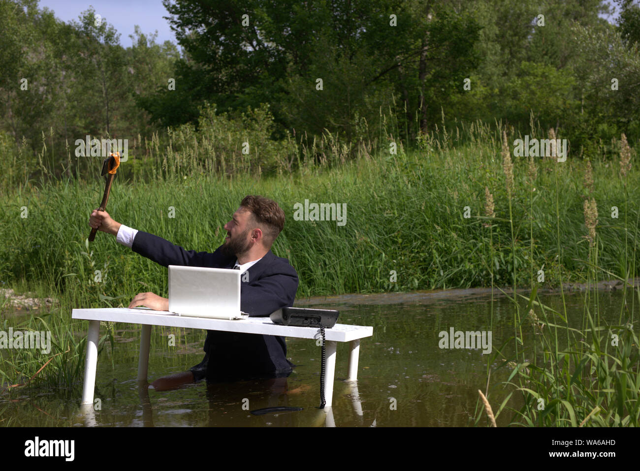 Jeune hipster barbu salons, distraite de travailler au bureau et prendre un. selfies À une table debout dans un marais dans l'eau Banque D'Images