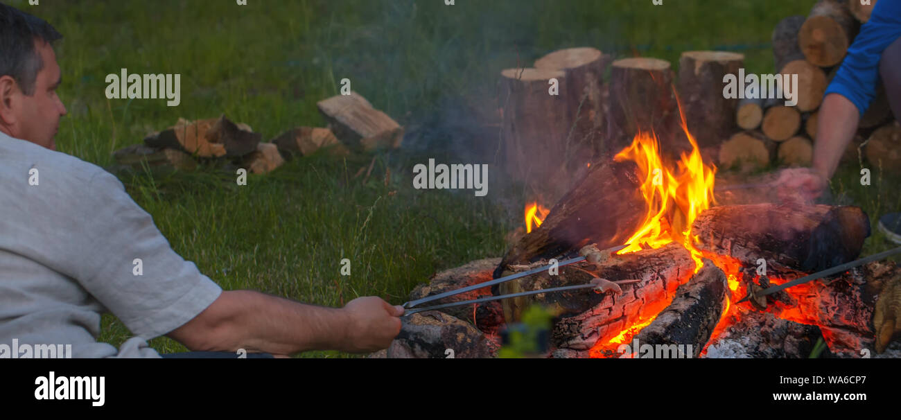 Deux amis sont assis autour d'un feu de camp et tout simplement se détendre Banque D'Images