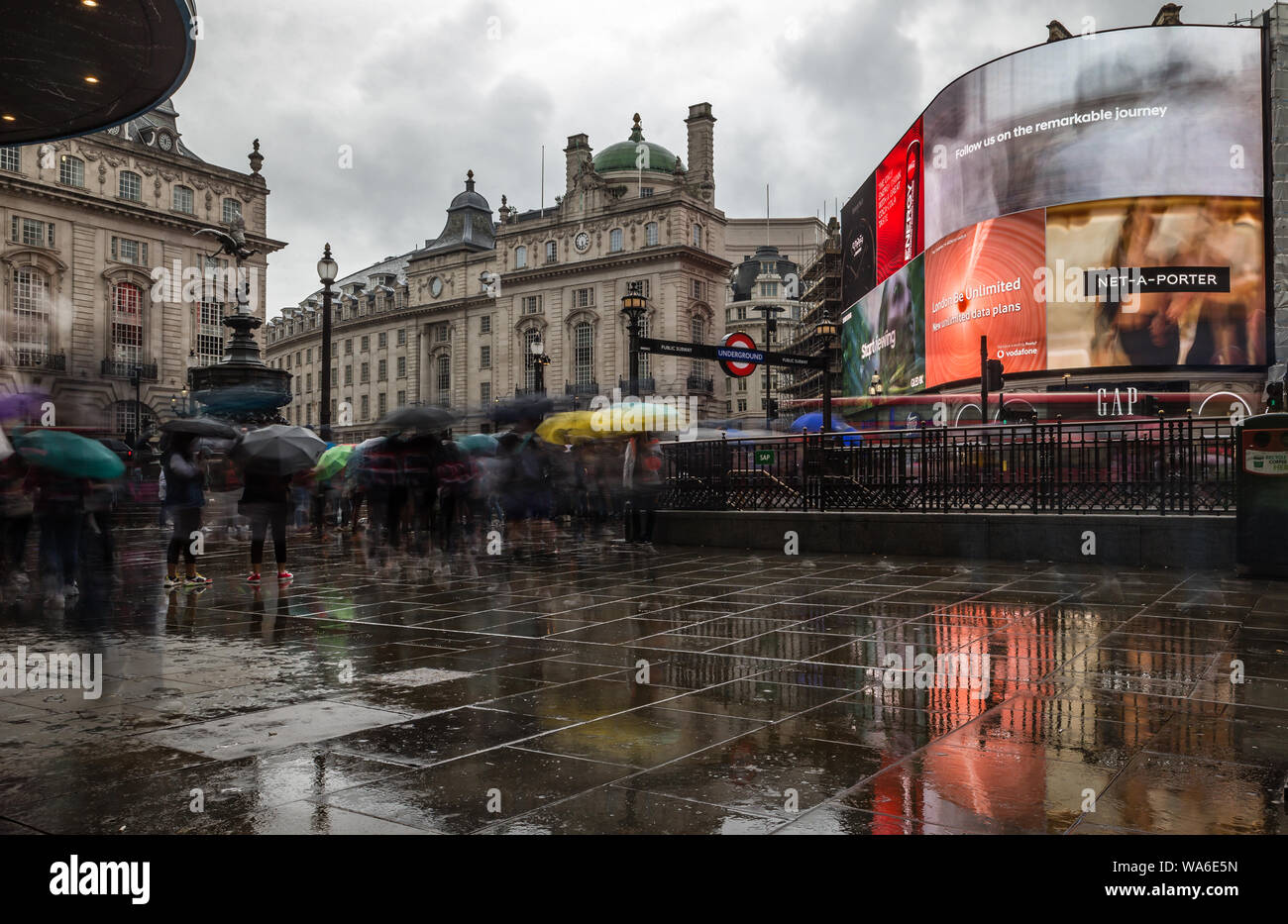 Parapluies haut comme la pluie descend dans Piccadilly Circus, Londres. Banque D'Images