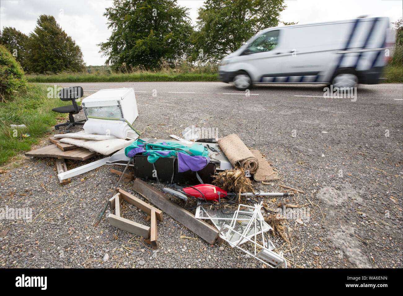 Passage d'un véhicule faisant l'objet d'ordures à côté d'une route de campagne dans le Dorset. Articles comprennent une télévision à écran plat, d'un président et de sac à dos. Dorset England UK GO Banque D'Images
